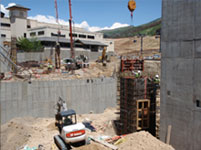 NWCC crew working on a job site to build a new cement block retaining wall using an excavator